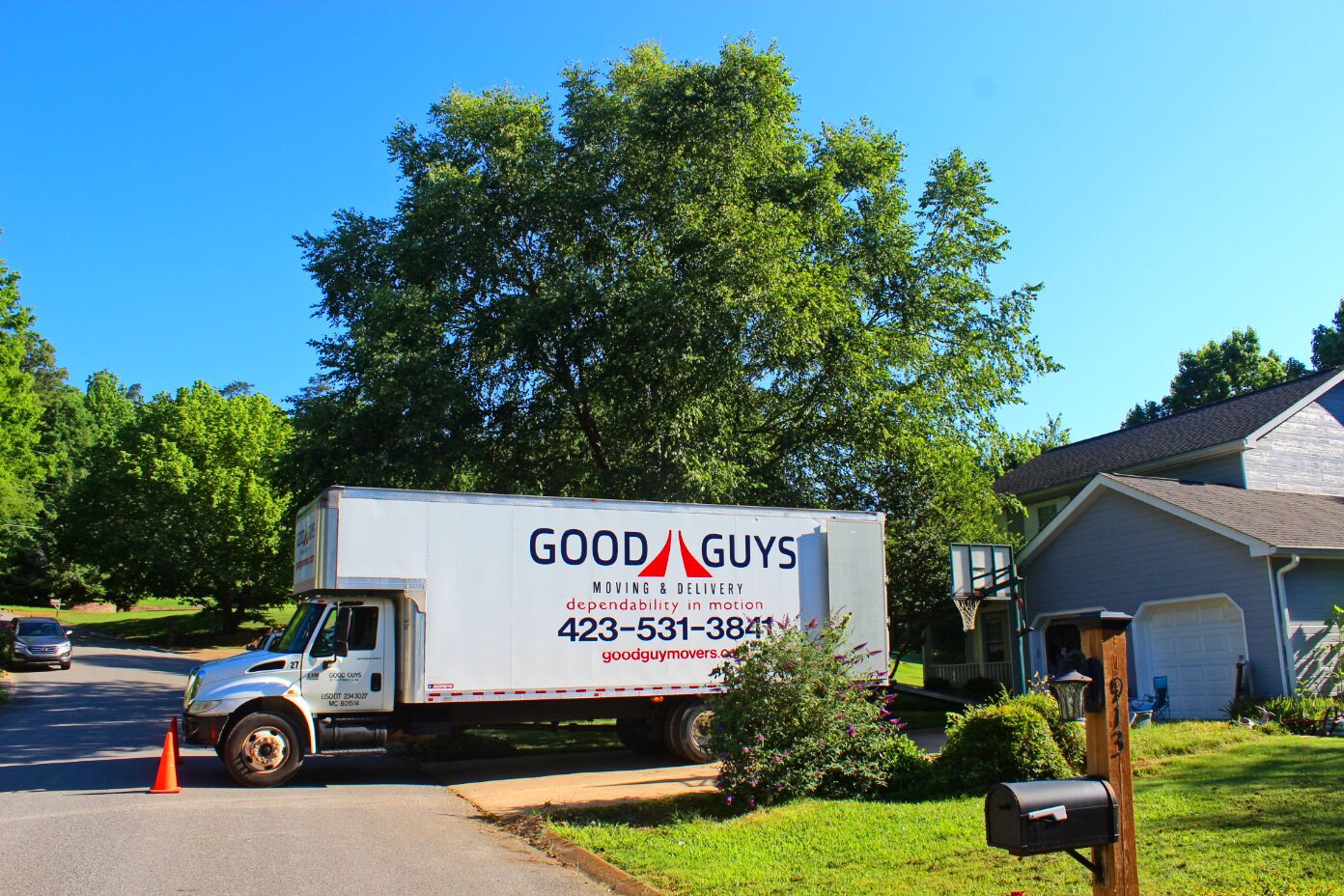 A Good Guys moving truck parked in a residential driveway on a sunny day.
