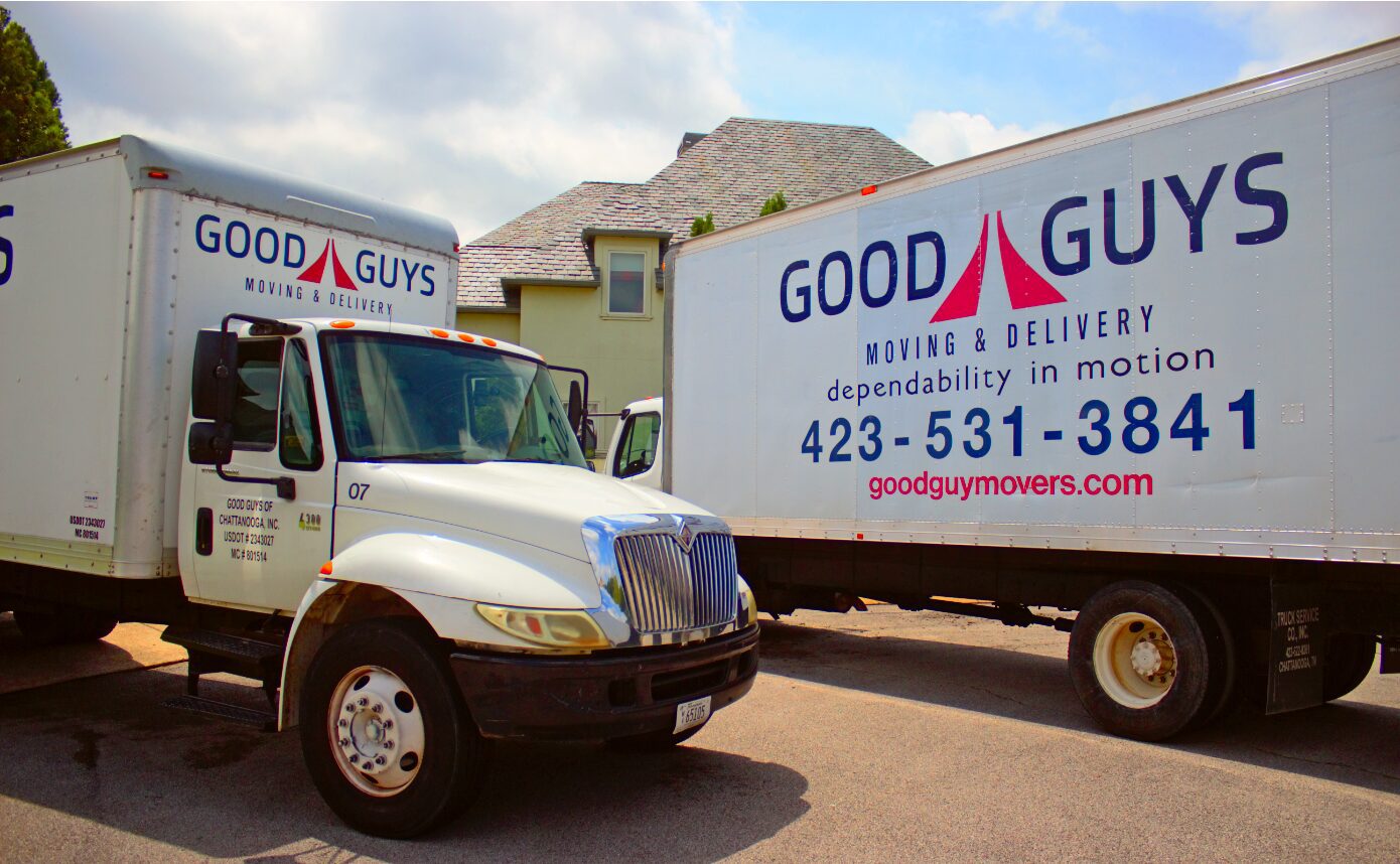 Two Good Guys moving trucks parked near a house.