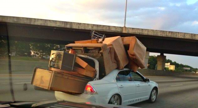 A car overloaded with furniture on its roof and trunk.
