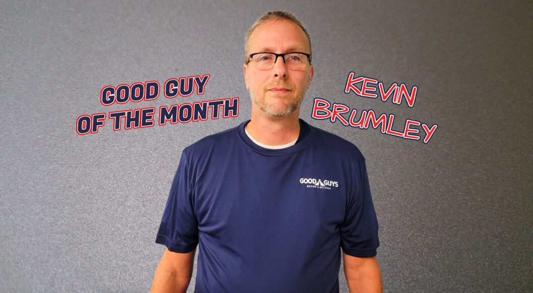 Man wearing glasses and blue shirt with 'Good Guy of the Month' text.